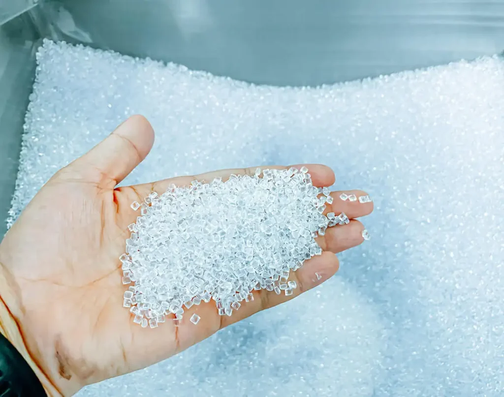 Granuli trasparenti di plastica termoplastica su una mano